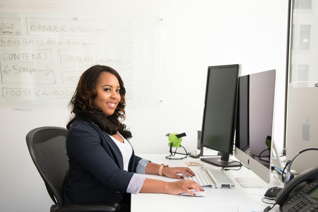 Confident businesswoman seated at her desk in an office, typing on a computer.
