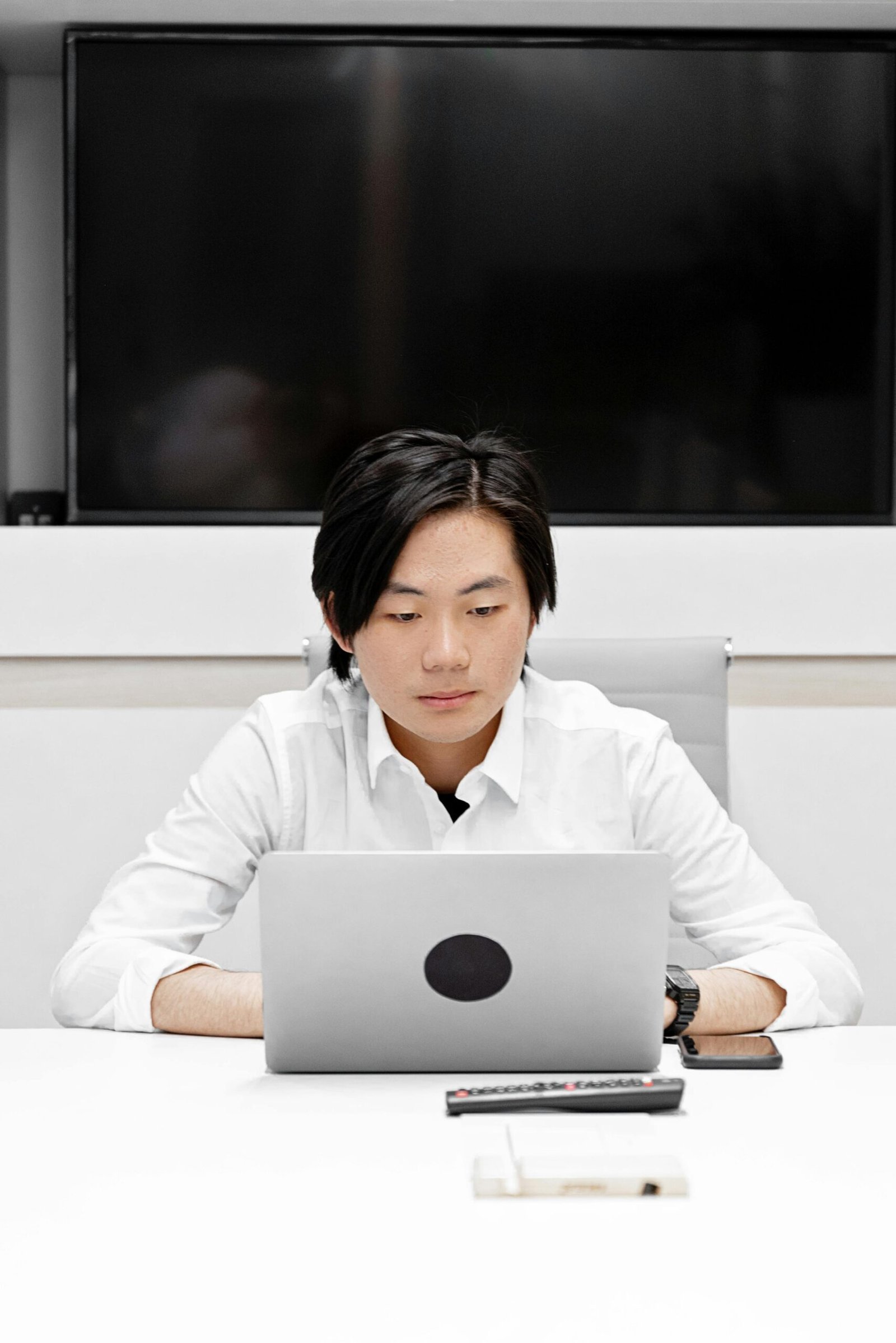 Asian man working inside office with laptop, illustrating a focused work environment.